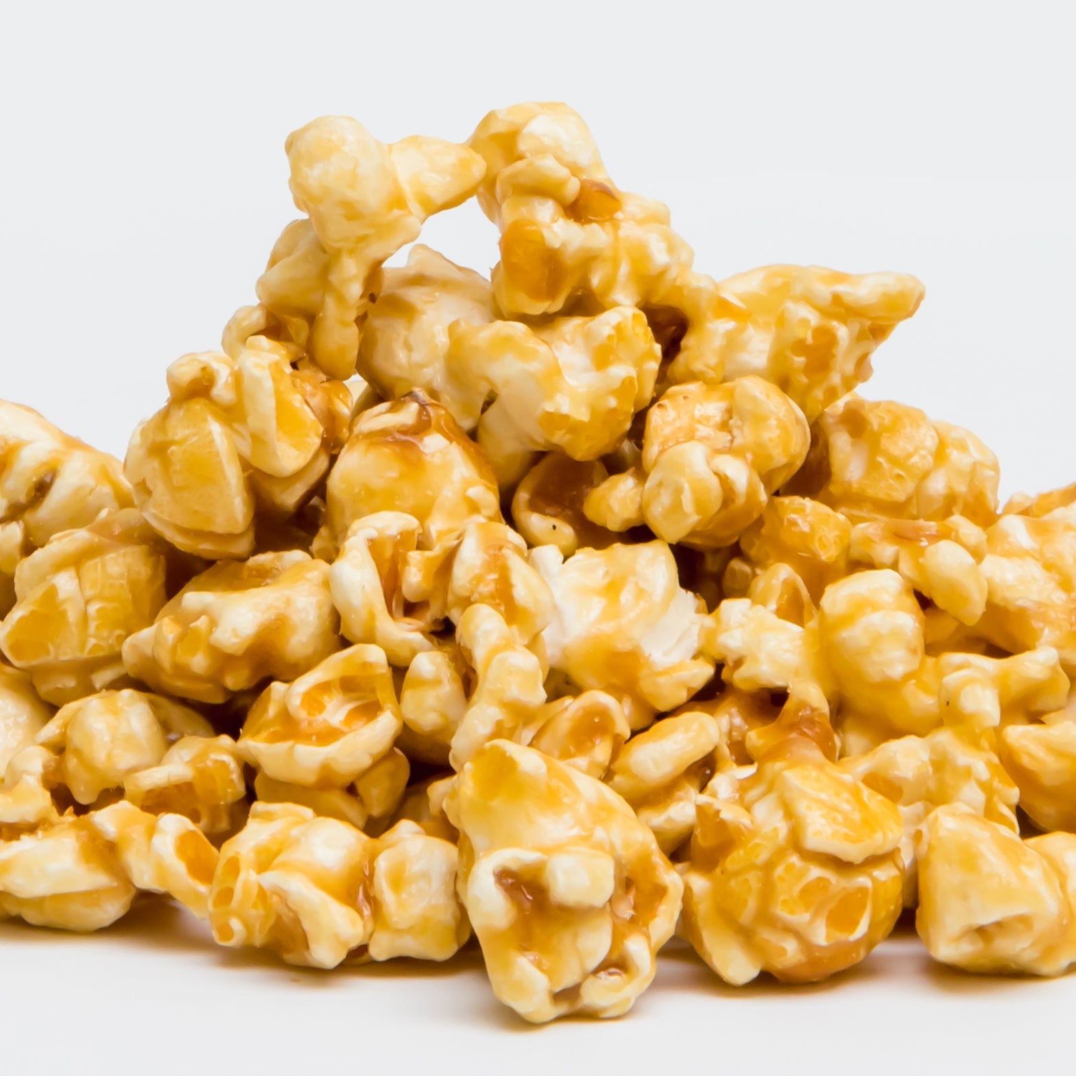 A pile of Caramel Popcorn from Colorado Popcorn Company sits on a plain white background, highlighting this classic treat.