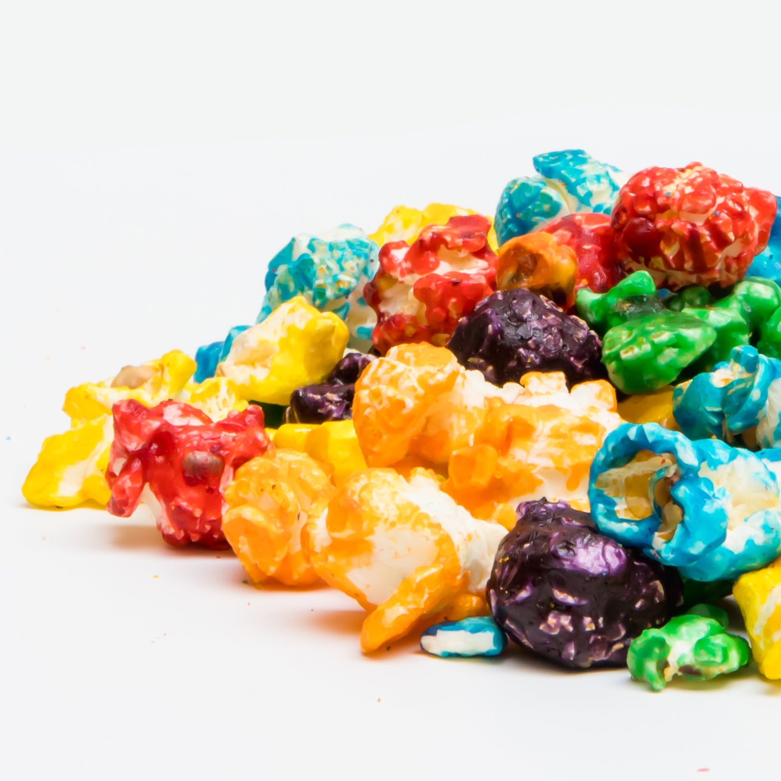 Tooti Fruiti Popcorn pieces in assorted vibrant colors are displayed on a white background, highlighting this fruity-flavored snack as a fun treat.