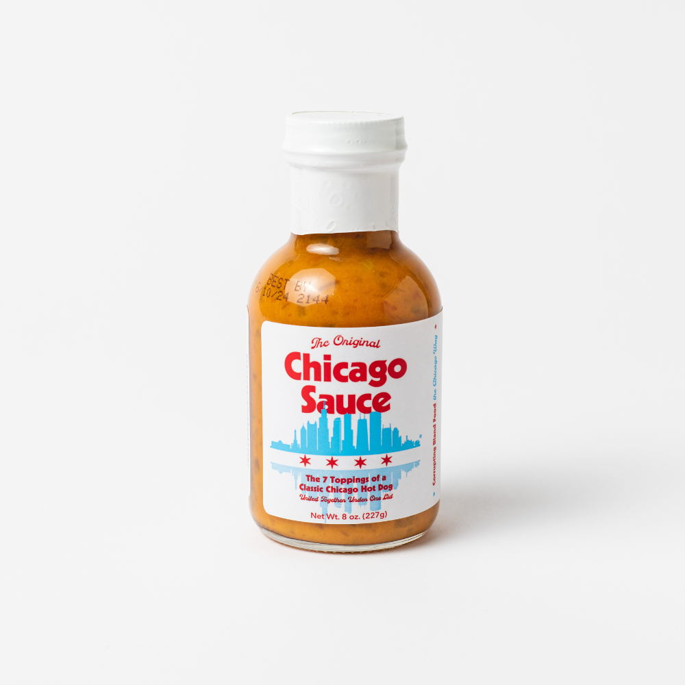 A bottle of The Original Chicago Sauce, The Real Windy City Sauce, with a white cap and a label featuring red and blue text, a city skyline silhouette, stars, and the note &quot;The Original&quot; for authentic Chicago flavor.