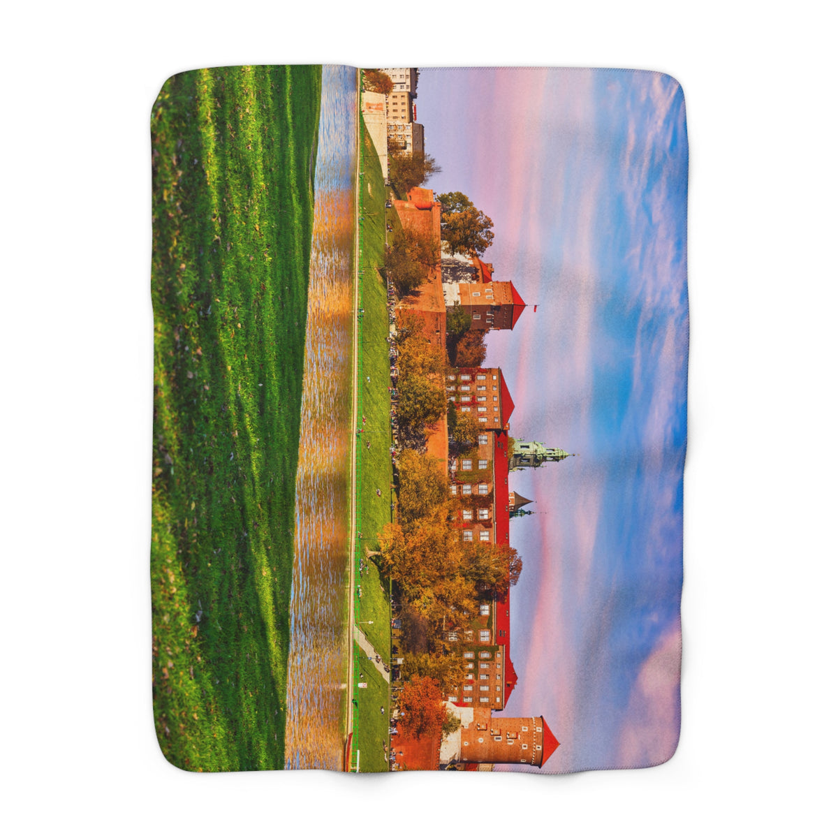 The Wawel Castle Sherpa Fleece Blanket showcases a vivid image of Wawel Castle’s red-brick towers, lush grass, and autumn trees under a colorful sunset sky—perfect for adding warmth and charm to any room.