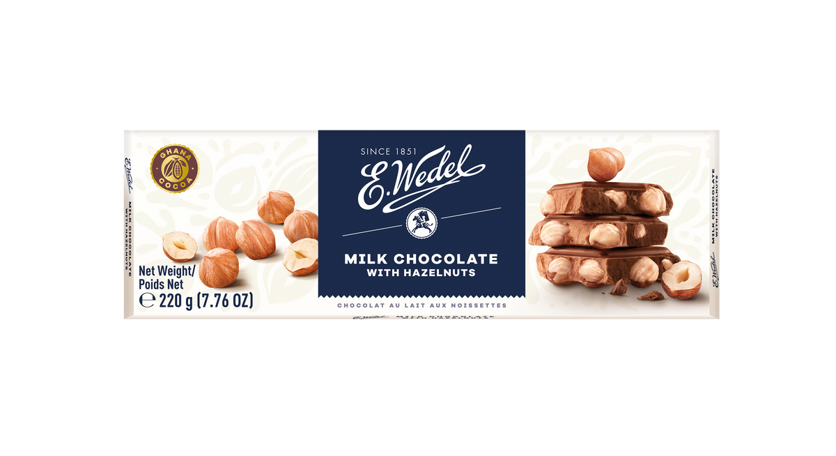 A Wedel Luksusowa Chocolate W/ Hazel 220g wrapper with the E. Wedel logo shows whole hazelnuts and stacked chocolate pieces, featuring "Milk Chocolate with Hazelnuts," net weight 220g (7.76 oz), and tempting hazel chocolate pieces.