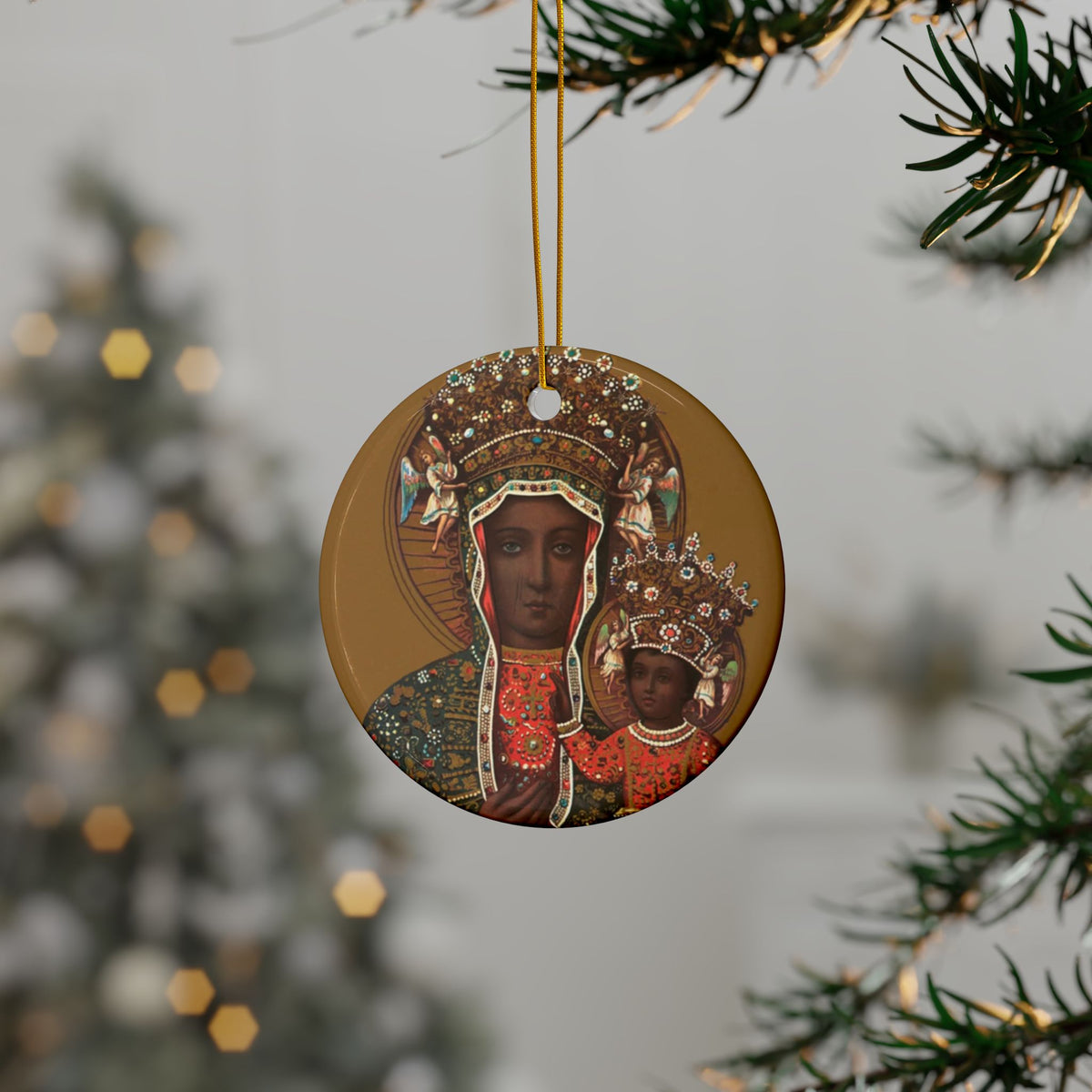 The Black Madonna of Częstochowa Ornament is a round ceramic decoration featuring the revered icon, hanging from a gold string on a tree branch—an ideal choice for adding unique holiday charm to your festive décor.