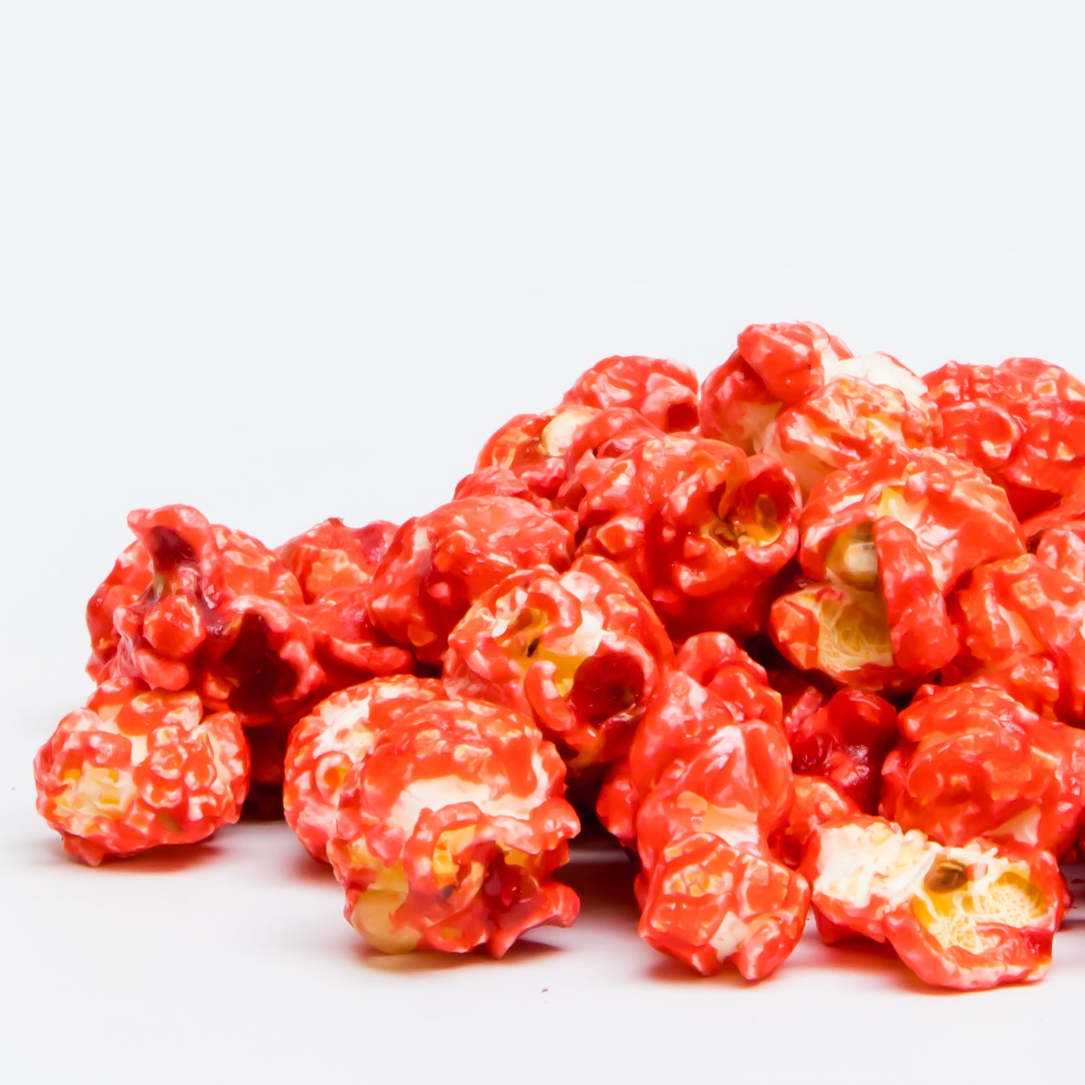 A pile of Cinnamon Popcorn, made from Non-GMO popcorn and real cinnamon oil, is displayed against a plain white background.