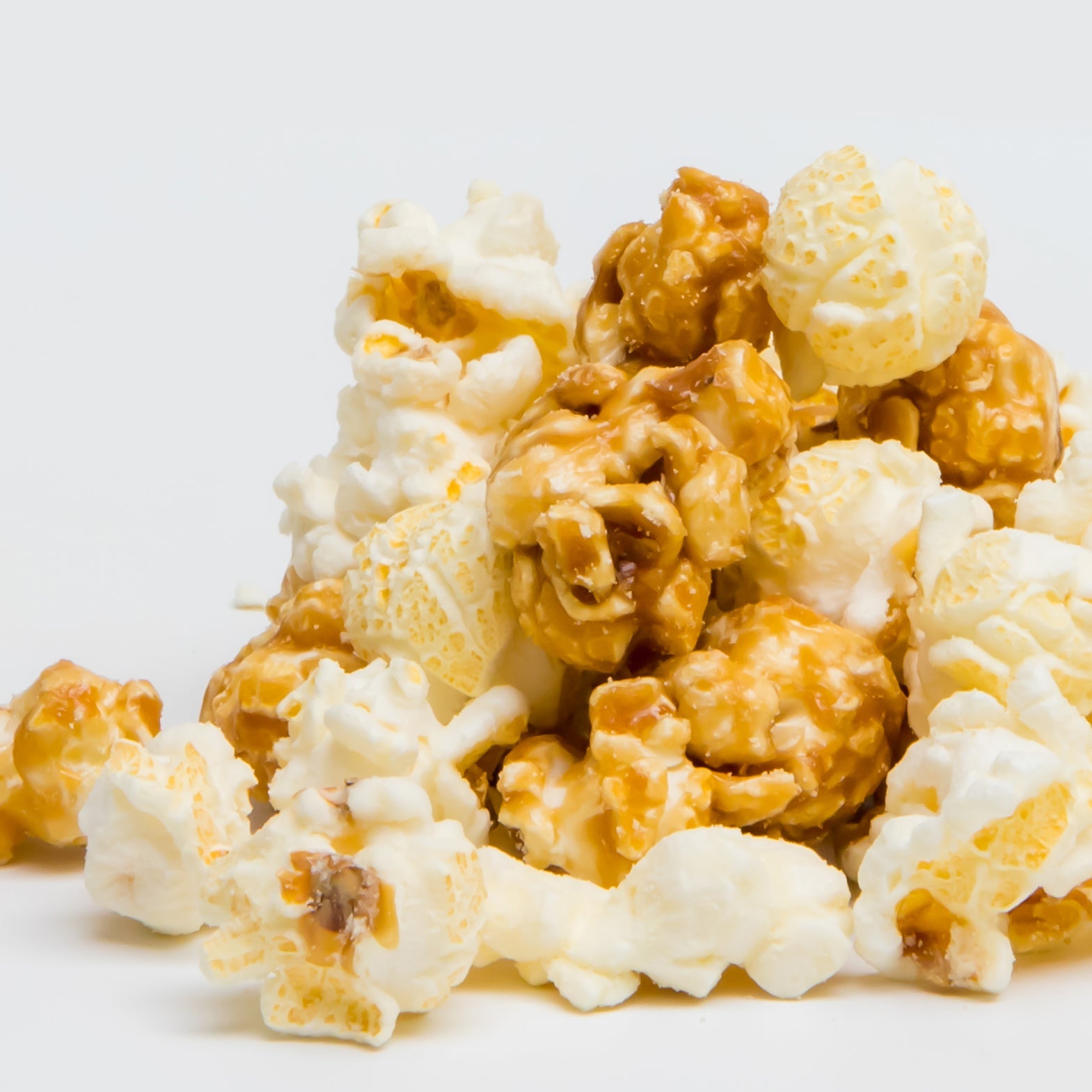 Colorado Style Popcorn, a blend of non-GMO caramel and plain popcorn, is shown piled against a white background.