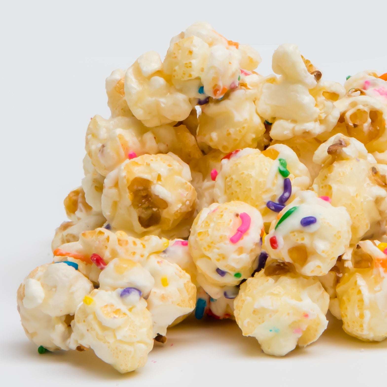 Birthday Cake Popcorn: Candied popcorn clusters covered in white chocolate glaze and colorful sprinkles, photographed on a plain white background—an irresistible treat for fans of Birthday Cake Popcorn.