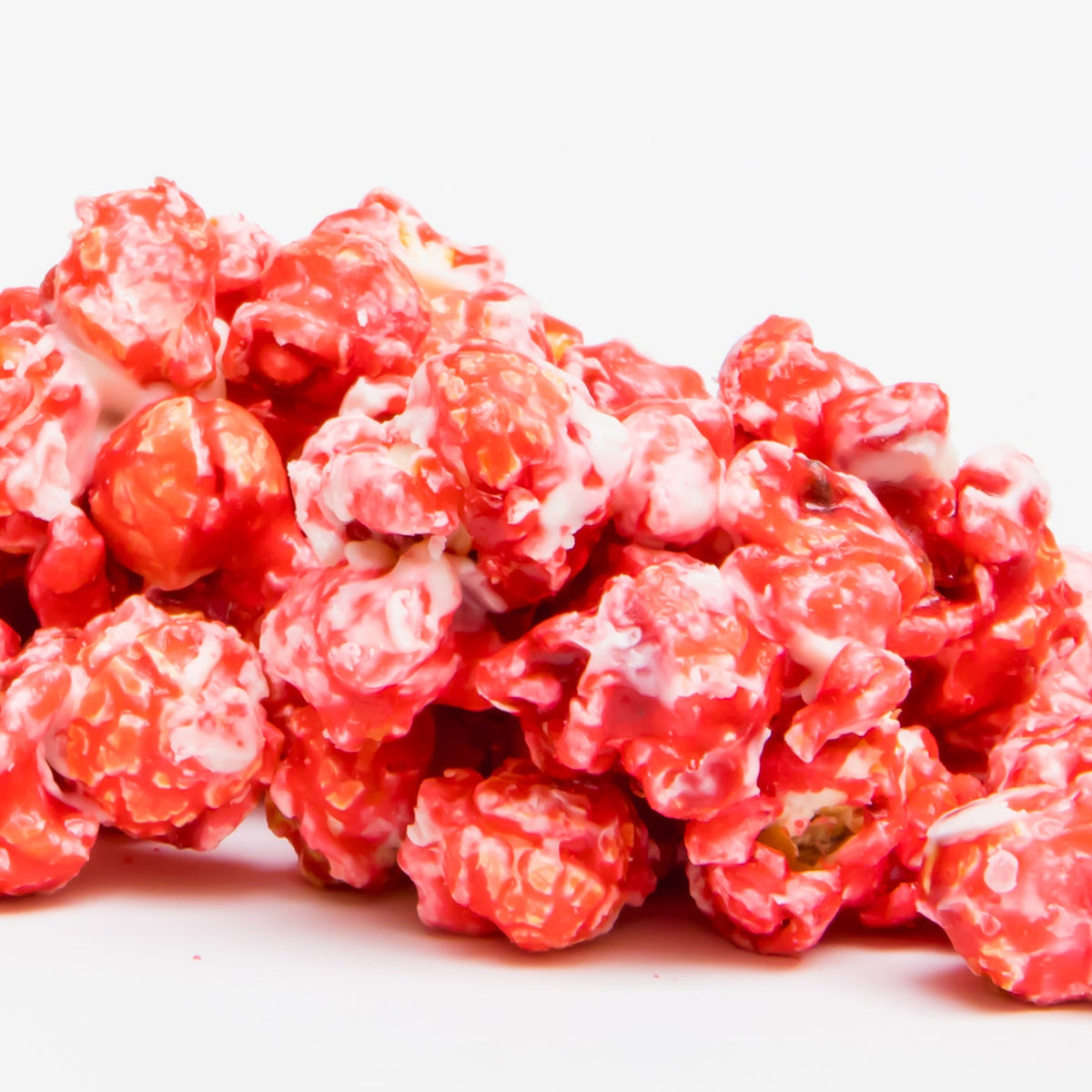Raspberry White Chocolate Popcorn is shown in a pile of red and white candy-coated pieces against a plain white background.