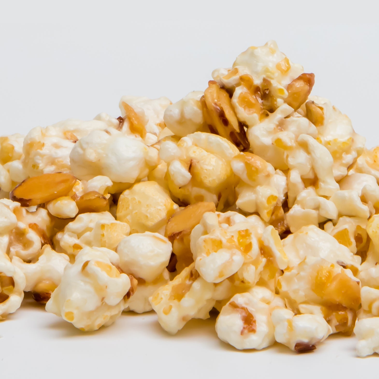 A close-up of Amaretto Popcorn on a plain white background highlights this irresistible snack featuring candied popcorn and sliced almonds.