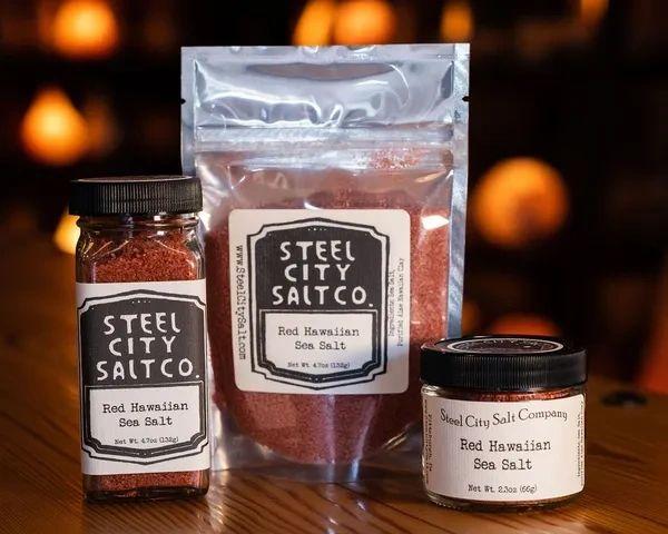 Three containers of Red Hawaiian Sea Salt—a jar, a resealable bag, and a small round jar—each with black and white labels, are arranged on a wooden surface against a warm, softly blurred background.