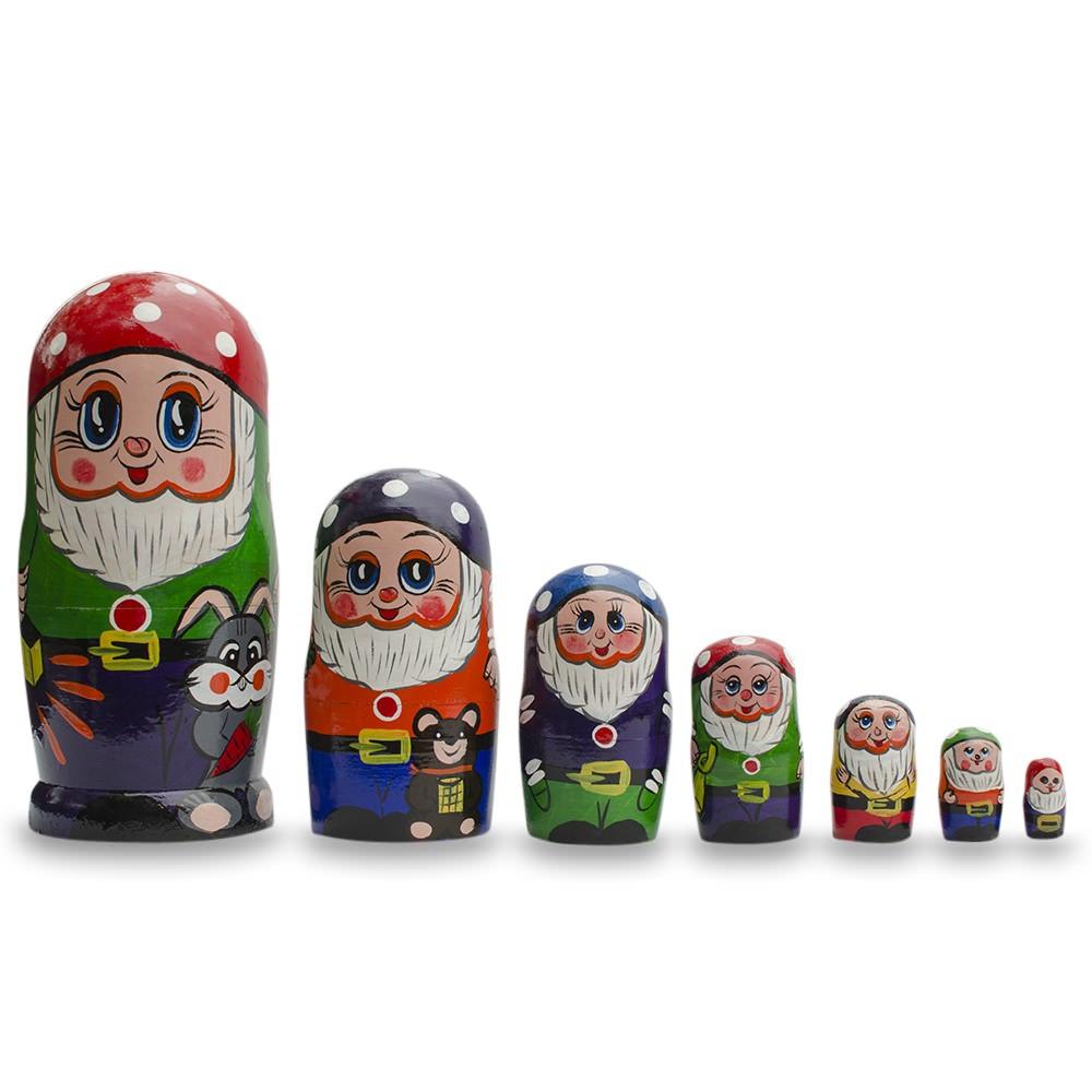 The Set of 7 Gnomes Wooden Nesting Dolls (8 Inches) features hand-painted linden wood dolls, each bearded gnome with a red hat and animals, nested by size from largest to smallest against a white background.